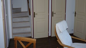 Une pièce comprenant une chaise en bois, un banc en bois et un escalier menant à une porte.