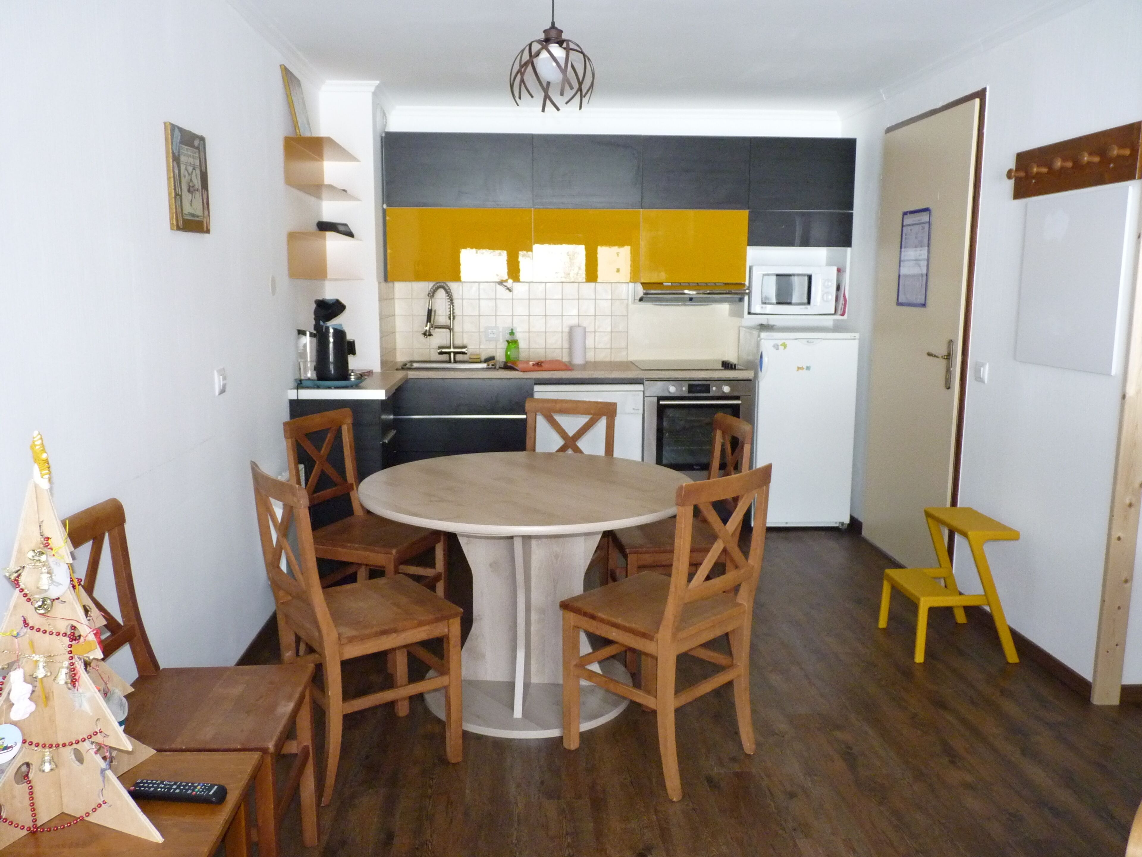 Une cuisine compacte avec une table à manger entourée de chaises, un four à micro-ondes, un four traditionnel et un évier.