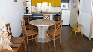Une cuisine compacte avec une table à manger entourée de chaises, un four à micro-ondes, un four traditionnel et un évier.