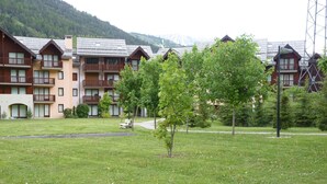 Un hôtel doté de nombreux balcons, d’une cour verdoyante et offrant une vue sur les montagnes.