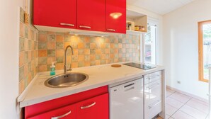 A kitchen with red cabinets, a stainless steel sink, and a dishwasher. - House garden garage 10 mn downtown (Nîmes)
