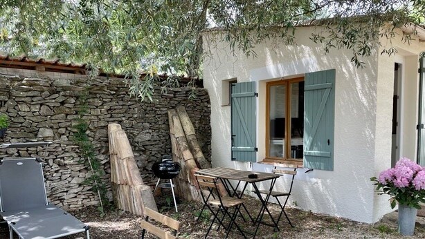 A rustic outdoor seating area with a stone wall, wooden furniture, and a small table. - House garden garage 10 mn downtown (Nîmes)