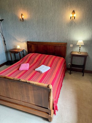 A neatly made bed with a wooden headboard, two bedside lamps, and a small table with a lamp. - Large family home (15 people) with swimming pool (La Dornac)