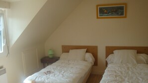 A bedroom with two single beds, a nightstand with a lamp, and a painting on the wall.