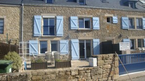 A stone building with multiple windows, some with shutters. There is a sign indicating it is a vacation residence.