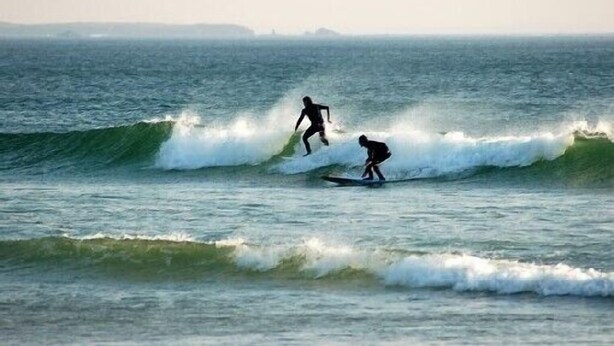 Two surfers riding waves in the ocean.