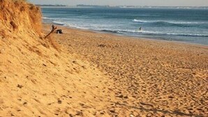 A sandy beach with dunes and the ocean in the background.