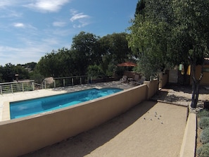 A rectangular swimming pool with a stone border, surrounded by a paved deck.