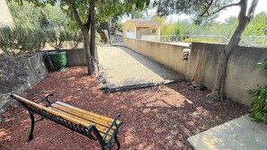An outdoor patio area with a wooden bench, a small shed, and a concrete wall. - Typical house - Swimming pool - Quiet location Nîmes on foot (Nîmes)