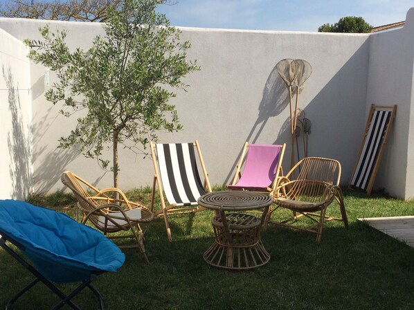 A patio with wicker furniture, a small table, and a fan. - Presqu'ile dans l'île, Pretty 3* house, town center, 4 pers, enclosed garden + garage (Loix)