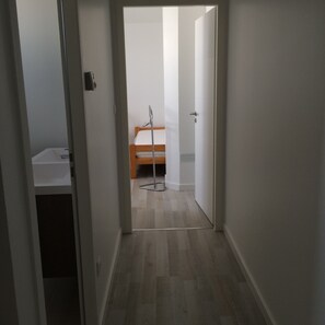 A narrow hallway with a wooden floor leading to a room with a bed and a bedside table. - Presqu'ile dans l'île, Pretty 3* house, town center, 4 pers, enclosed garden + garage (Loix)