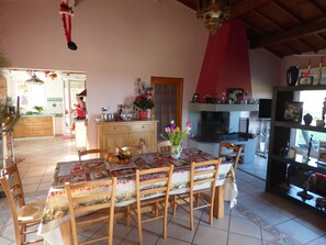 A dining area with a table set for four, surrounded by wooden chairs. A wooden cabinet with drawers is visible in the background.