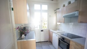 Una cocina con armarios de madera, lavavajillas, horno y una ventana con luz natural.
