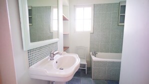 Un baño con lavamanos, espejo y bañera.