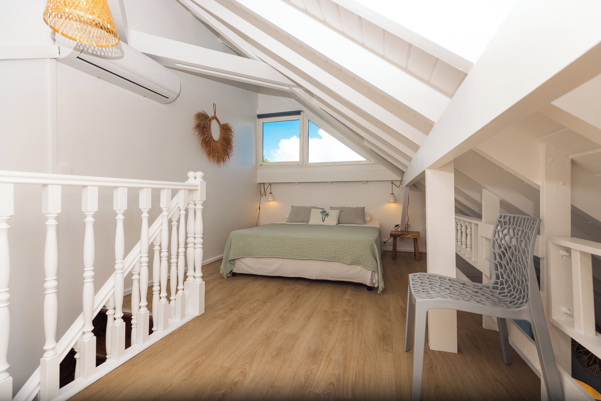 A bedroom with a bed, a chair, a window, and a staircase.