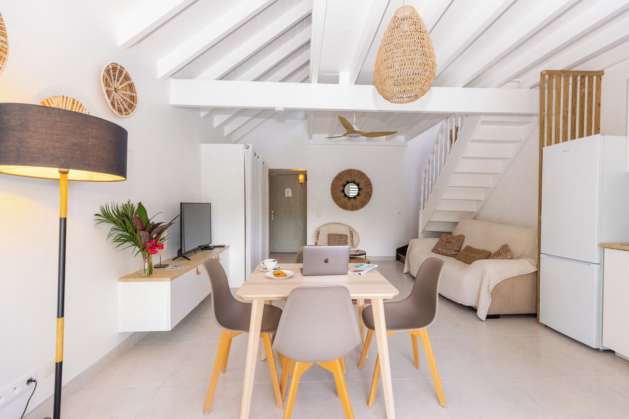 A modern kitchen with a dining area, white cabinetry, and a staircase.