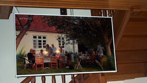 A dining area with tables and chairs, a staircase, and a building with a red roof. - Maison Pyrénées, 3*, south-facing, Mosquito nets, Fibre, Livebox, 2Tv, Enclosed park. (Ossun-Ez-Angles)