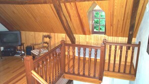 A wooden interior with a staircase, a television, and a window with a view of greenery. - Maison Pyrénées, 3*, south-facing, Mosquito nets, Fibre, Livebox, 2Tv, Enclosed park. (Ossun-Ez-Angles)