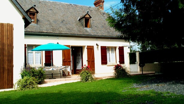 A two-story house with a sloped roof, a wooden fence, and a small garden with a table and umbrella. - Maison Pyrénées, 3*, south-facing, Mosquito nets, Fibre, Livebox, 2Tv, Enclosed park. (Ossun-Ez-Angles)