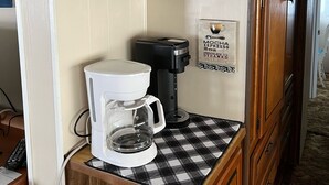 A kitchenette with a coffee maker, tea kettle, and various mugs and containers on shelves. - Ocean Lakes Cottage Quiet Street, Shady Lot, 5000 Section Sleeps 7 (Myrtle Beach)
