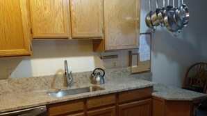 A kitchen with wooden cabinets, a granite countertop, a stainless steel dishwasher, and a tiled floor. - Oaks at Wasatch--call for discounted monthly off-season corporate rates (Cottonwood Heights)