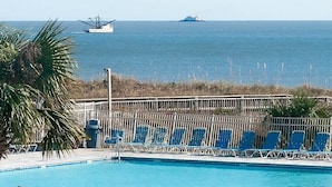 Una piscina con sedie blu e vista sull'oceano.
