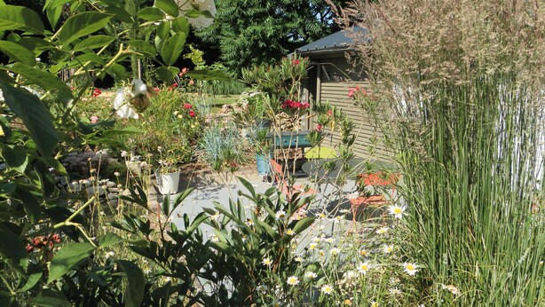 A garden with various plants and flowers, a wooden structure, and a stone wall. - CHARMING COUNTRY HOUSE WITH WIFI (Perche En Nocé)
