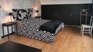 A bedroom with a bed, a nightstand, a chair, a mirror, and a wall sign. - CHARMING COUNTRY HOUSE WITH WIFI (Perche En Nocé)