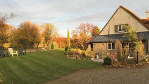 A house with a well-maintained lawn, a small garden, and outdoor seating. - CHARMING COUNTRY HOUSE WITH WIFI (Perche En Nocé)