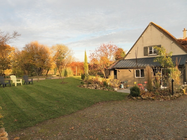 A house with a well-maintained lawn, a small garden, and outdoor seating.
