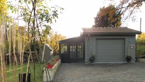 A small, single-story building with a garage, a covered porch, and a gravel driveway. - CHARMING COUNTRY HOUSE WITH WIFI (Perche En Nocé)