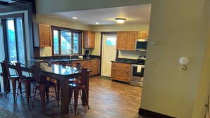 A spacious kitchen with wooden cabinets, a large island, and a dining area with chairs. - Veranda 4 Bedroom Unit 1 (Lake Placid)