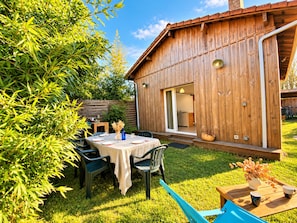 A wooden building with a sliding door entrance, a table set for dining, and a chair.
