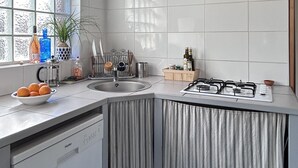 A modern kitchen with a built-in dishwasher, a gas stove, and a window with decorative glass panels. - Peace, Beaches and Cycling on the Bay of Arcachon - Arès Cap Ferret  (Arès)