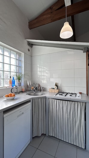 Een moderne keuken met een inbouwvaatwasser, een gasfornuis en een raam met decoratieve glaspanelen.