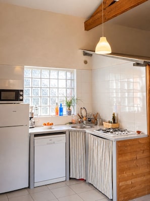 A kitchen with a built-in microwave, a dishwasher, a sink, and a stove. There is a window with frosted glass and a hanging pendant light.