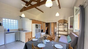 A cozy kitchen with wooden beams, a dining table set for two, and a bookshelf. - Peace, Beaches and Cycling on the Bay of Arcachon - Arès Cap Ferret  (Arès)