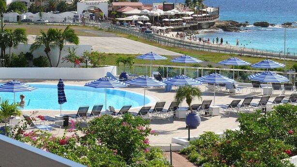 Un complexe hôtelier doté d’une piscine, de chaises longues et offrant une vue sur l’océan.