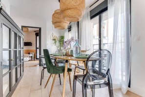A dining area with a wooden table, green and black chairs, and a woven pendant light.