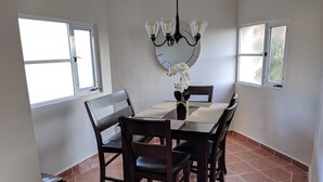 Ein Essbereich mit einem rechteckigen Tisch, vier Stühlen, einer Deckenleuchte und einer Wanduhr.