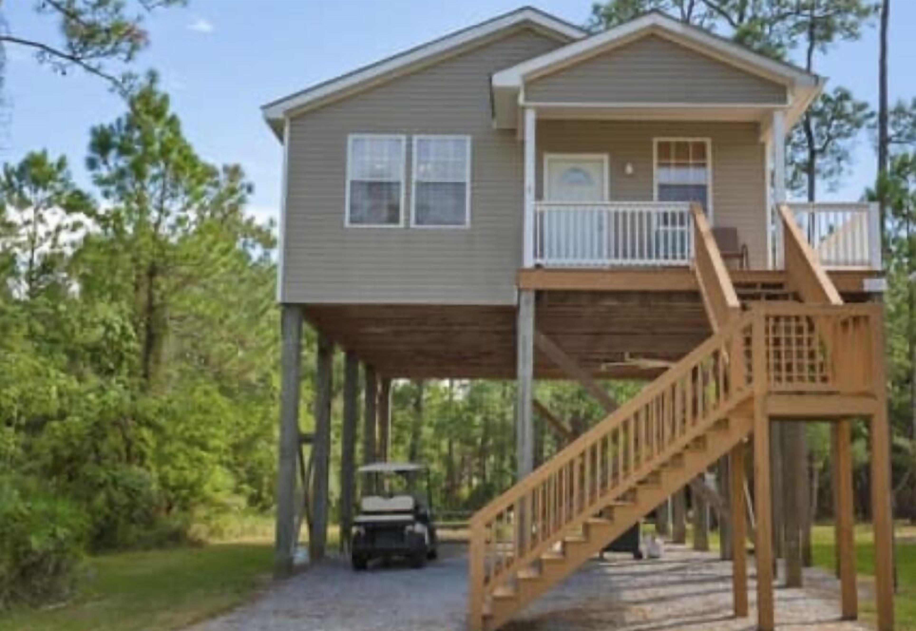 A two-story house with a wooden deck and a staircase leading to a balcony.