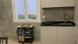 Una cuina compacta amb finestra, un rentaplat i una petita zona de menjador.