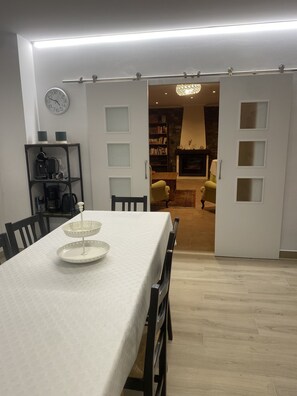 Un coin repas avec une table dressée pour deux personnes, une bibliothèque et une cheminée en arrière-plan.