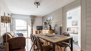 Ett mysigt vardagsrum med ett matbord i trä, bruna läderstolar, en soffa och en tv.
