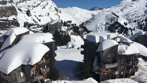 Un pueblo cubierto de nieve con edificios de madera y pistas de esquí.