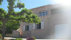 A two-story building with a stone-paved entrance, a balcony, and a garage. - Ground floor villa flat in Monticello (Monticello)
