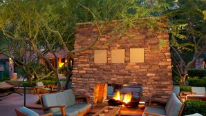 Un área de estar al aire libre con muros de piedra, una chimenea y sillones.