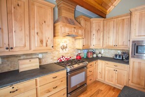 Enjoy cooking in this well-equipped kitchen with a central island, stainless steel stove, and ample countertop space.