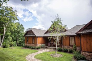 Surrounded by lush trees, this cabin features a covered porch and a well-manicured lawn.