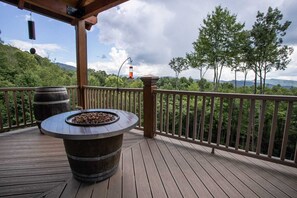 Enjoy the serene forest views from this deck, which offers a cozy fire pit and a lantern for ambiance.